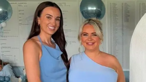 McGillivray Family Chelsea McGillivray and Lorna McGillivray. They are wearing blue dresses and smiling at the camera. There are blue balloons in the background.
