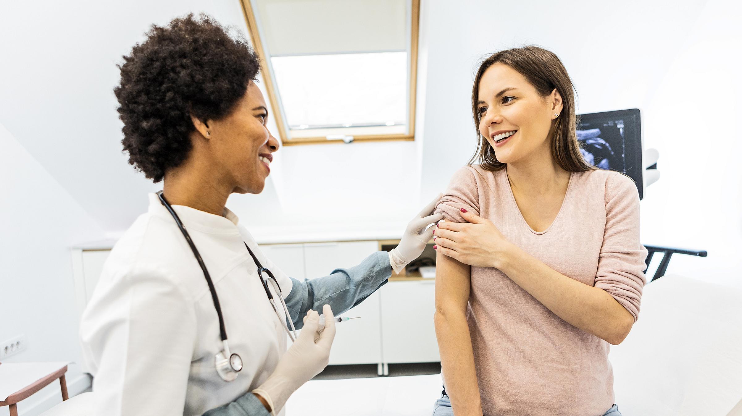 female doctor preparing a pregnant woman for vaccination